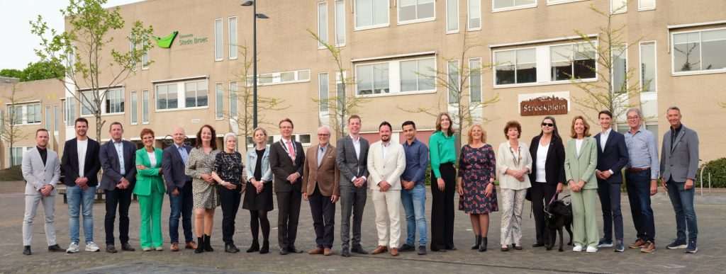 Gemeenteraadsleden poseren voor gemeentehuis op het Streekplein